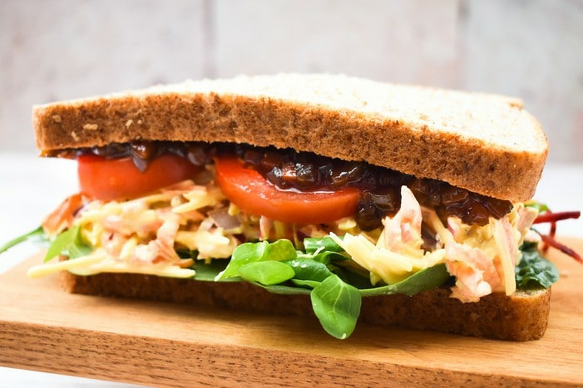 Cheese savoury in a brown bread sandwich with salad and pickle.