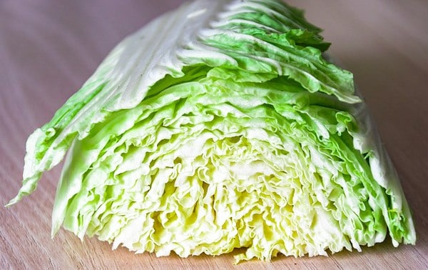 Half a head of cabbage on a wooden cutting board.