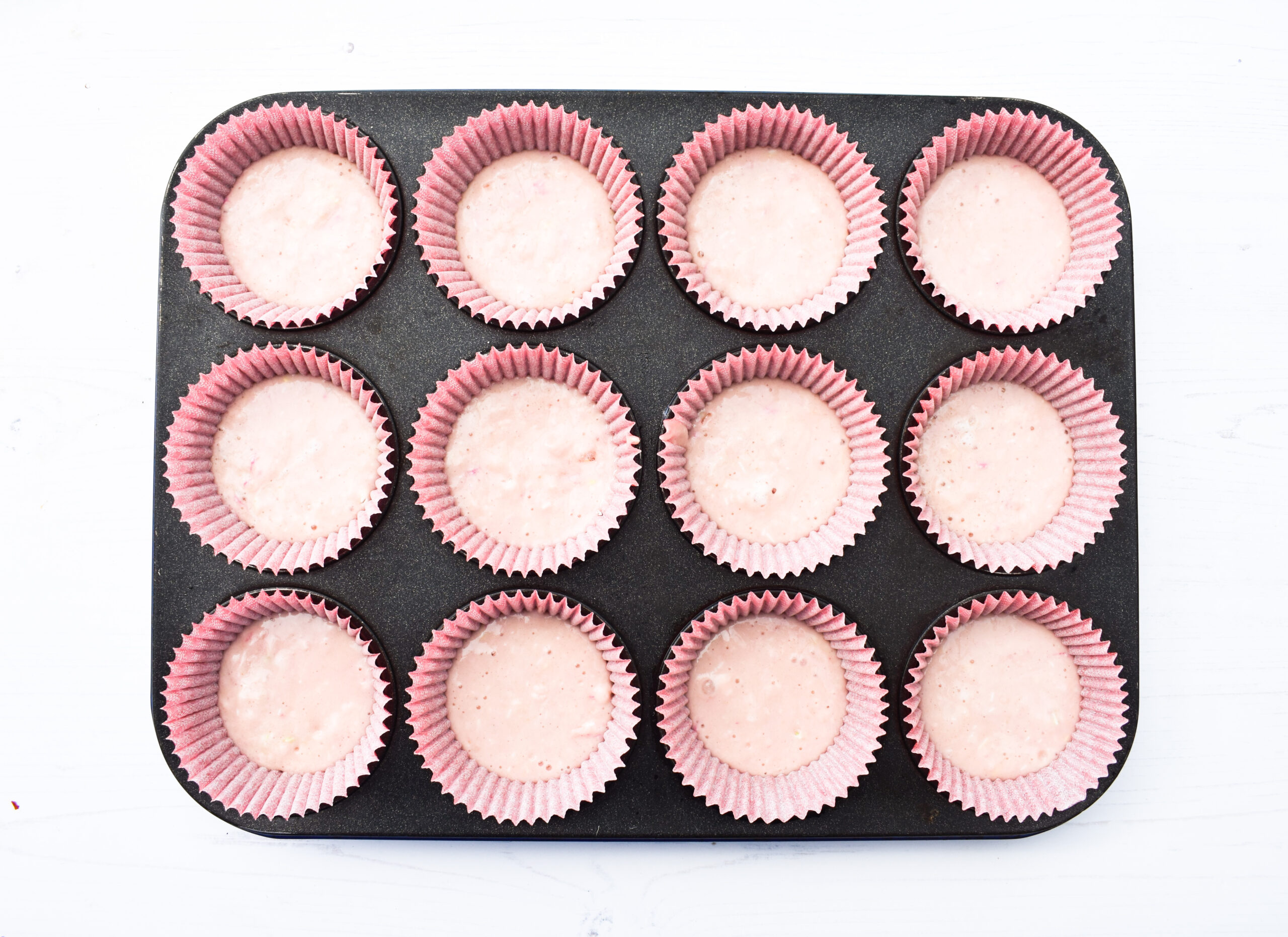 muffin cases half filled with muffin batter,
