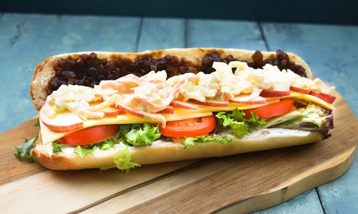 a ploughman's sandwich made on a baguette with added apple slices and slaw.