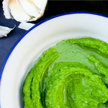 bowl of homemade cashew pesto next to a head of garlic.