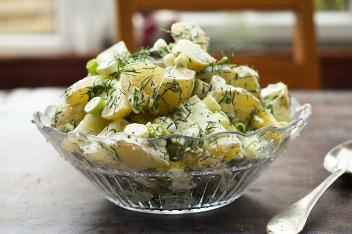 Homemade vegan dill potato salad heaped in a glass bowl.