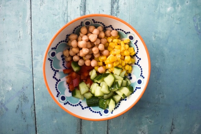 Making vegan macaroni step 3 - chickpeas and cucumber pieces added to the bowl.
