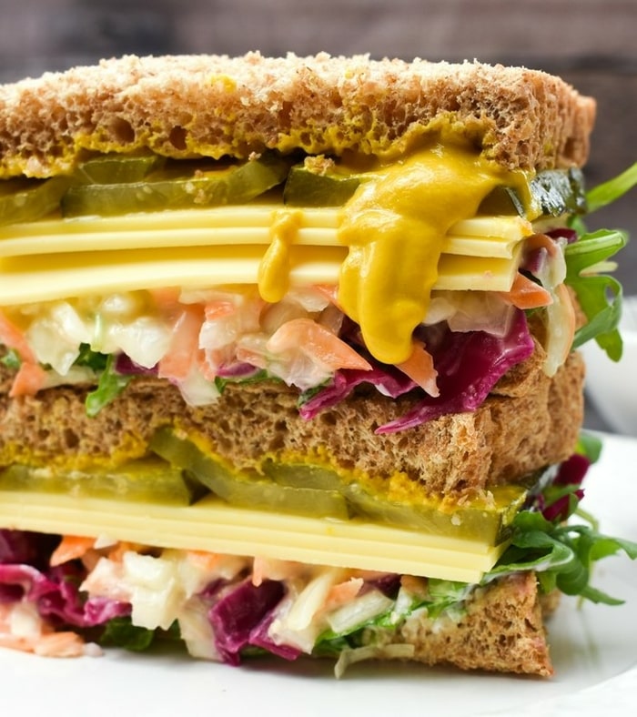 A close up of a vegan New York deli sandiwhich with mustard oozing out