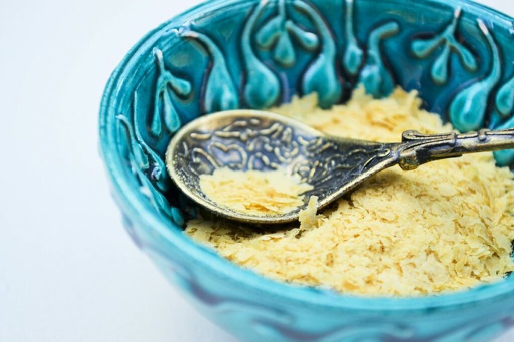 Nutritional yeast flakes in a small bowl with spoon