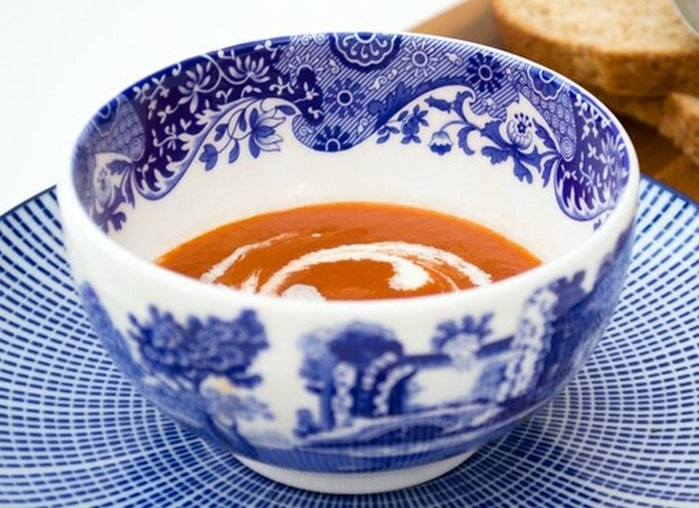 Vegan tomato soup topped with a swirl of cream, in a bowl.
