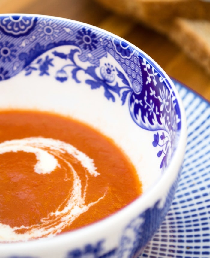 Vegan tomato soup made with canned tomatoes topped with a swirl of crem and served with brown bread.