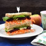 Hummus, beetroot and salad sandwich served with a red apple
