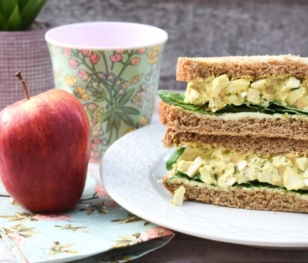 vegan egg mayo sandwich served with an apple and water