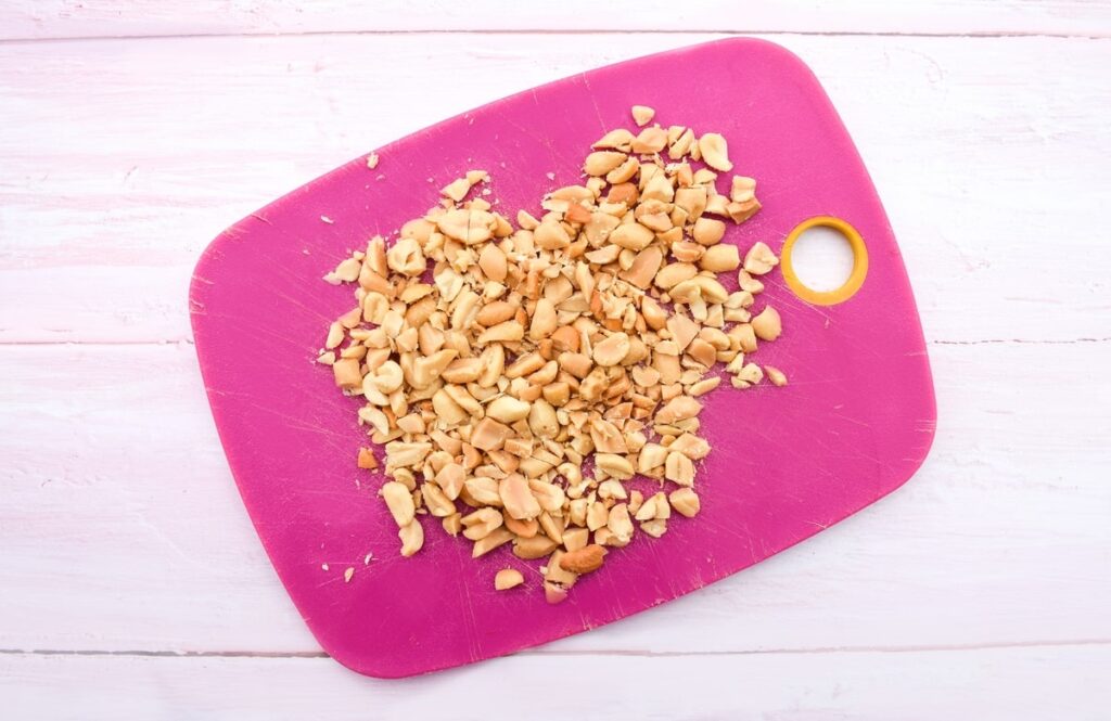 chopped peanuts on a pink chopping board