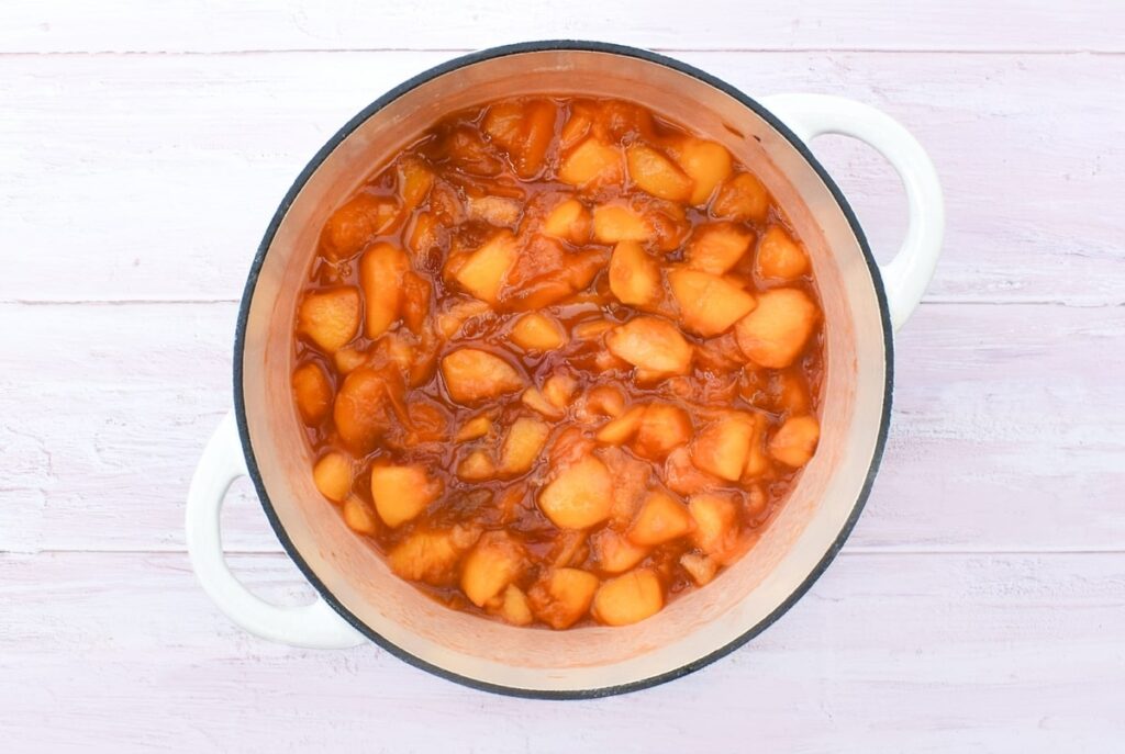 cooked peaches in a white cast iron pan