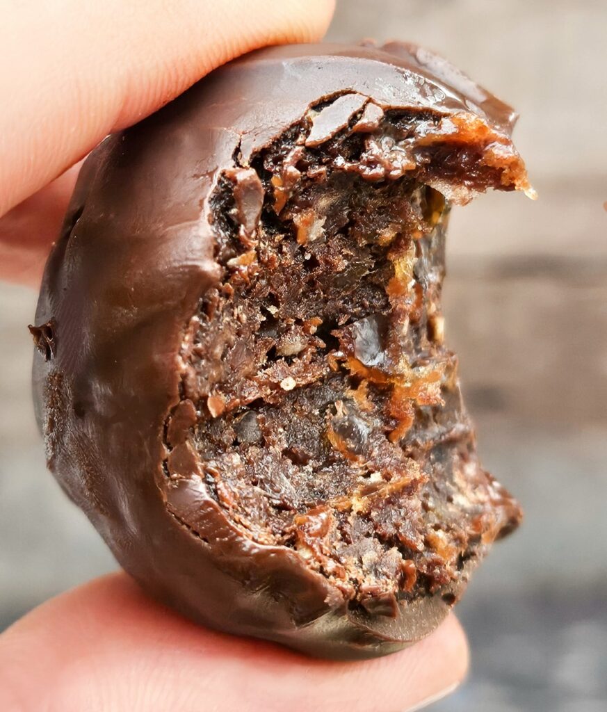 Healthier no-bake brownie ball bitten into, so you can see the chewy centre.