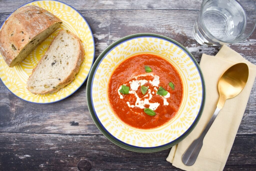 Vegan roasted red pepper soup in a bowl served with crusty bread.