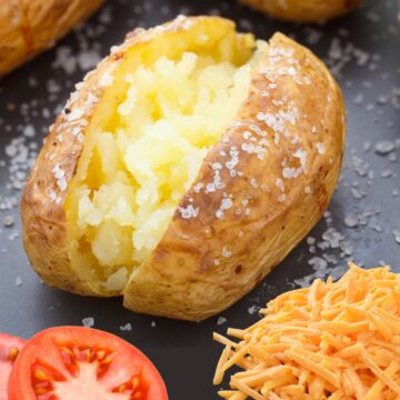jacket potato next to tomato slices and grated cheddar.