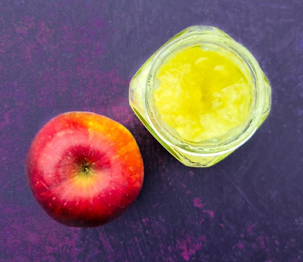 red apple and a jar of apple sauce.